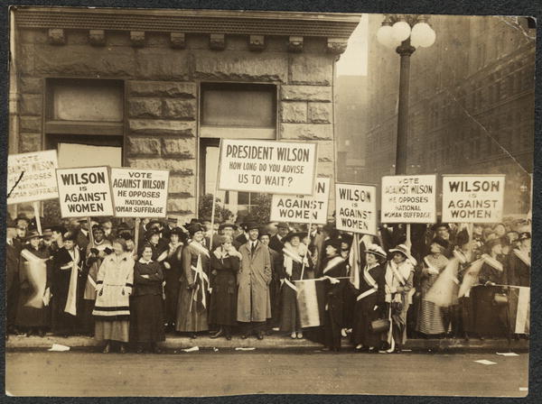 Suffragettes carrying signs.